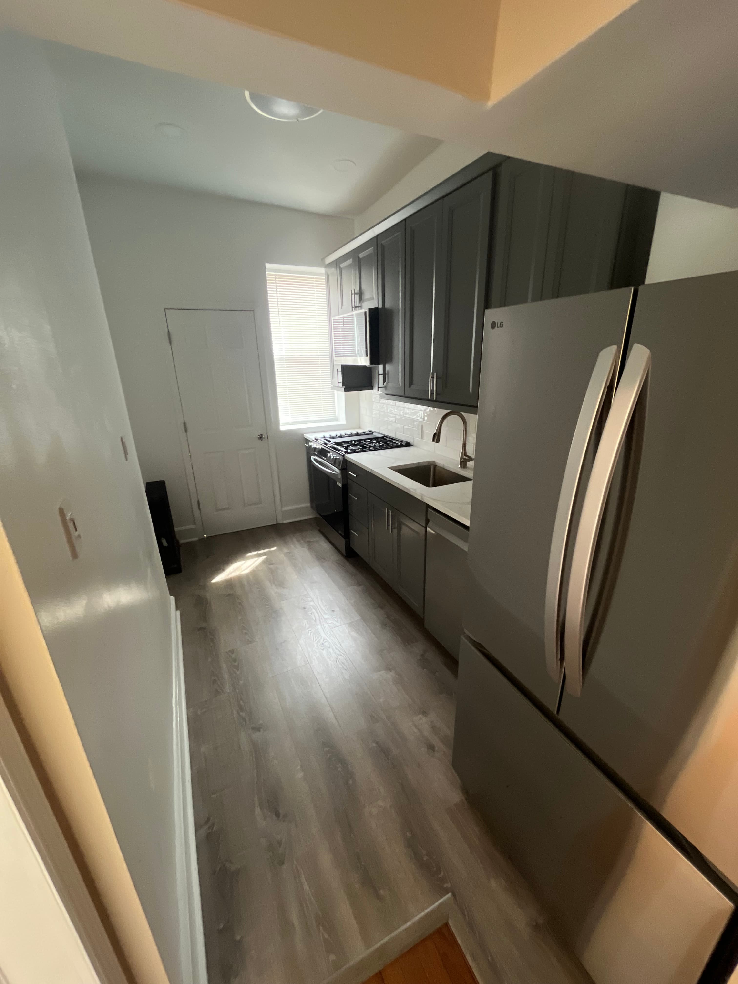 Finished kitchen with hardwood floors, white cabinetry, and stone countertops