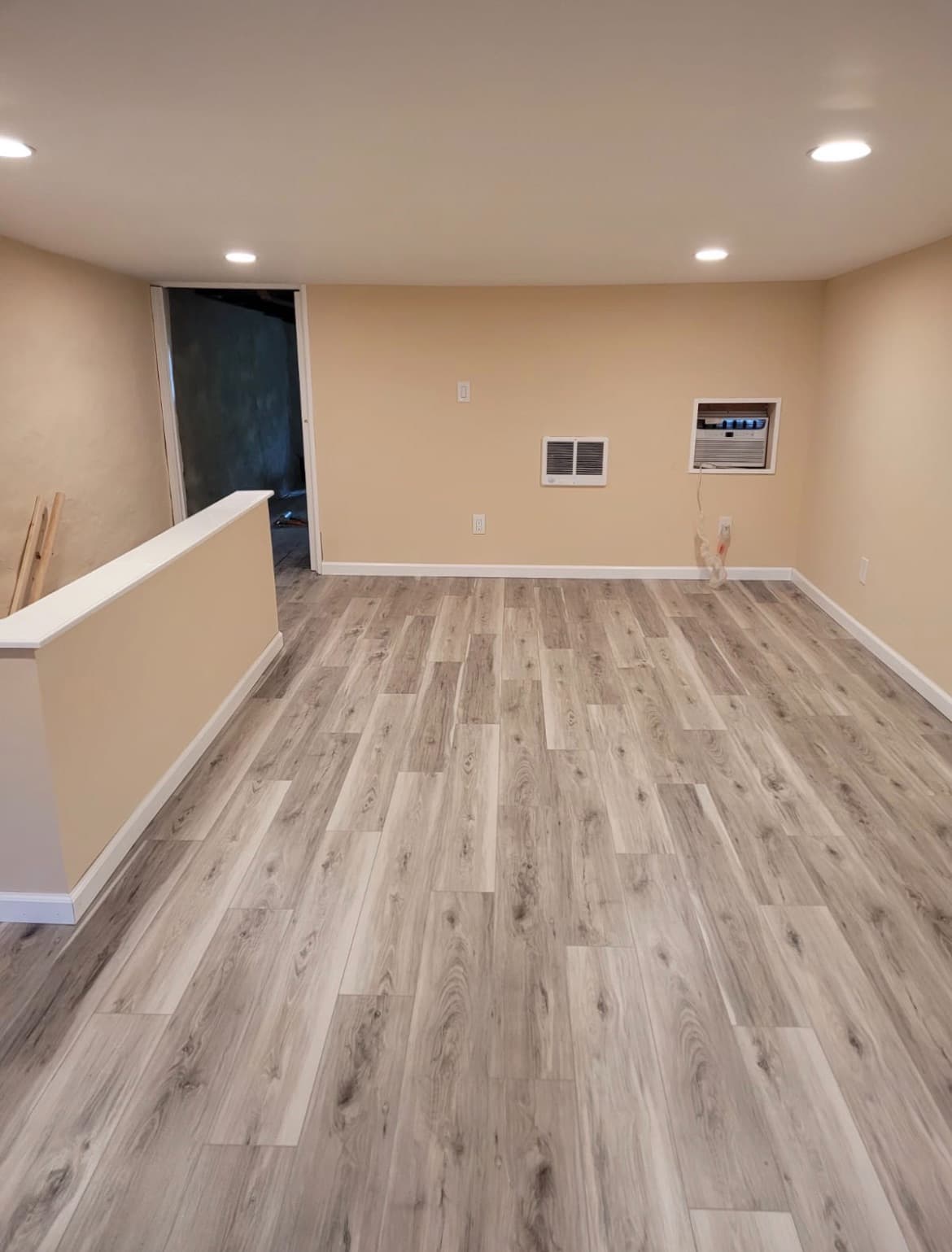 Finished basement room with luxury vinyl plank flooring and recessed lighting
